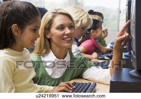 Teacher helping student at computer terminal with students in background (depth of field/high key) View Large Photo Image Stock Image - Teacher helping student at computer terminal with students in background (depth of field/high key). Fotosearch