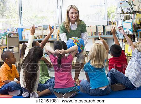 Stock Image - Teacher in class with students volunteering. Fotosearch