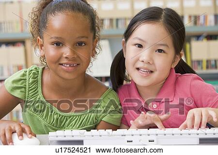 Stock Image - Two students in class at computer keyboard. Fotosearch