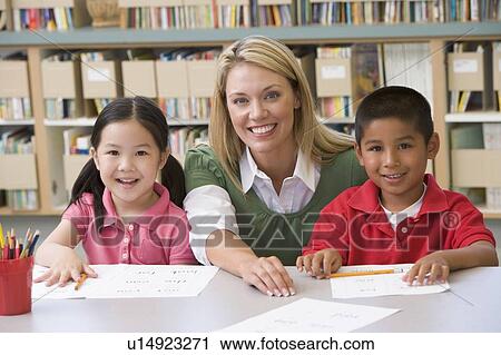 Stock Image - Two students in class with teacher. Fotosearch