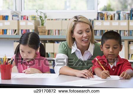 Two students in class writing with teacher helping View Large Photo Image Stock Image - Two students in class writing with teacher helping. Fotosearch
