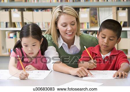 Two students in class writing with teacher helping View Large Photo Image Stock Image - Two students in class writing with teacher helping. Fotosearch