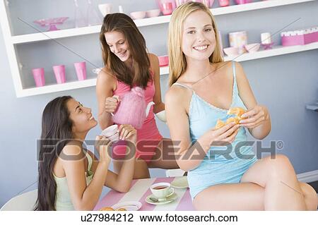 Three young woman sitting at a table having tea and a snack View Large Photo Image Stock Image - Three young woman sitting at a table having tea and a snack. Fotosearch