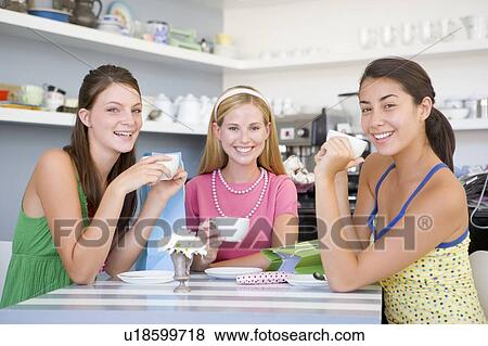 Stock Photo - Three young woman sitting at a table and drinking tea. Fotosearch
