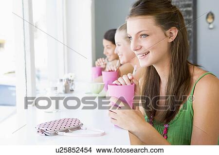Three young women having a cold drink in a cafeteria View Large Photo Image Picture - Three young women having a cold drink in a cafeteria. Fotosearch