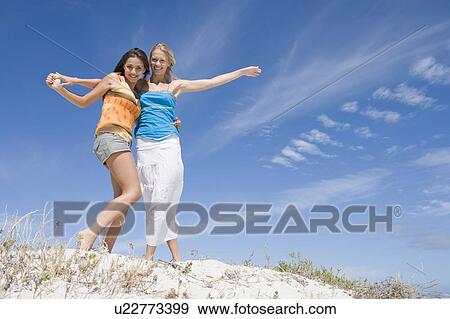 Stock Photo - Two young women posing on a sand hill. Fotosearch