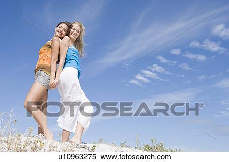 Two young women posing on a sand hill View Large Photo Image Stock Photography - Two young women posing on a sand hill. Fotosearch