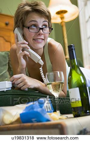 Stock Photo - Young woman at home talking on telephone. Fotosearch