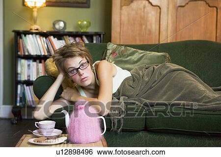 Stock Photograph - Young woman lying on sofa at home. Fotosearch
