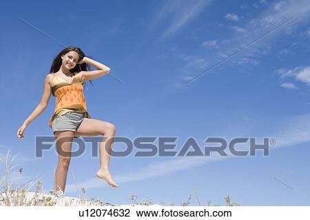 Stock Image - Young woman posing on a sand hill. Fotosearch
