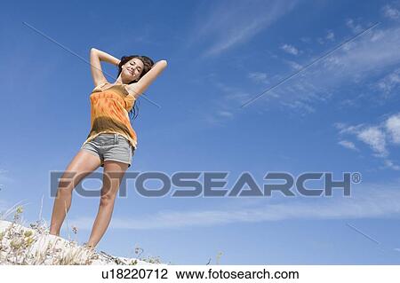 Stock Image - Young woman posing on a sand hill. Fotosearch