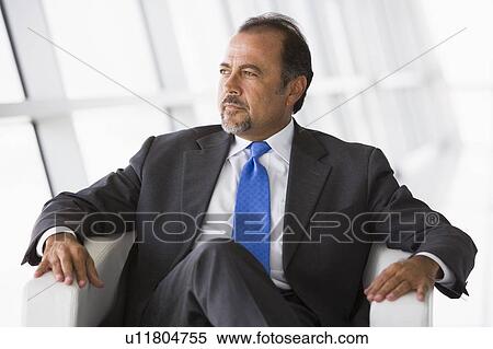 Businessman sitting indoors looking out window (high key/selective focus) View Large Photo Image Stock Photography - Businessman sitting indoors looking out window (high key/selective focus). Fotosearch