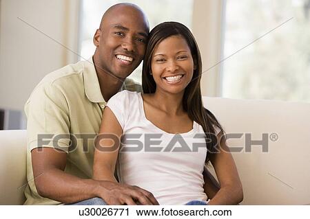 Stock Image - Couple in living room smiling. Fotosearch