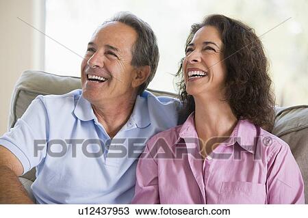 Couple relaxing in living room and laughing View Large Photo Image Stock Image - Couple relaxing in living room and laughing. Fotosearch