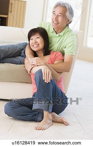 Stock Photo - Couple relaxing in living room and smiling. Fotosearch