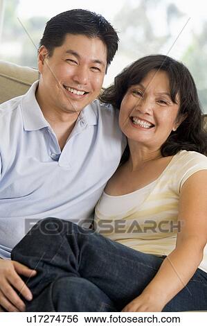 Stock Photograph - Couple relaxing in living room and smiling. Fotosearch