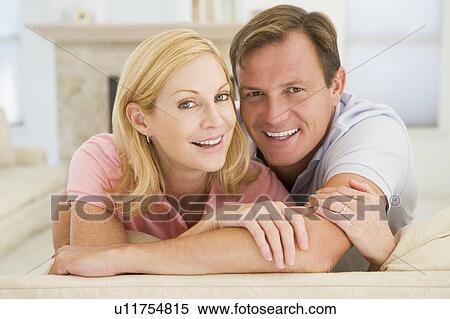 Couple relaxing in living room and smiling View Large Photo Image Stock Photography - Couple relaxing in living room and smiling. Fotosearch