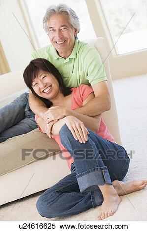 Stock Photography - Couple relaxing in living room and smiling. Fotosearch