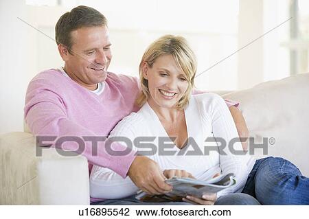 Couple relaxing with a magazine and smiling View Large Photo Image Stock Image - Couple relaxing with a magazine and smiling. Fotosearch