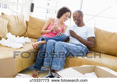 Couple relaxing with champagne by boxes in new home smiling View Large Photo Image Stock Image - Couple relaxing with champagne by boxes in new home smiling. Fotosearch