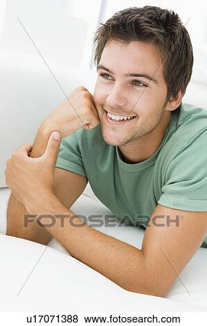 Man lying in living room smiling View Large Photo Image Stock Photo - Man lying in living room smiling. Fotosearch