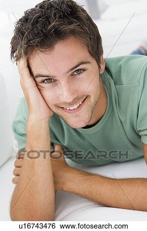 Stock Photograph - Man lying in living room smiling. Fotosearch