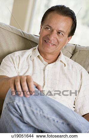Man sitting in living room smiling View Large Photo Image Picture - Man sitting in living room smiling. Fotosearch