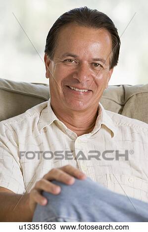 Man sitting in living room smiling View Large Photo Image Stock Image - Man sitting in living room smiling. Fotosearch