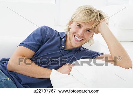 Man sitting in living room smiling View Large Photo Image Stock Photo - Man sitting in living room smiling. Fotosearch