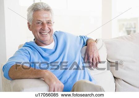 Stock Photography - Man sitting in living room smiling. Fotosearch