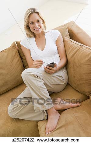 Woman in living room using personal digital assistant smiling View Large Photo Image Stock Image - Woman in living room using personal digital assistant smiling. Fotosearch