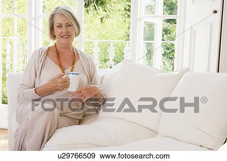 Woman in living room with coffee smiling View Large Photo Image Stock Photo - Woman in living room with coffee smiling. Fotosearch