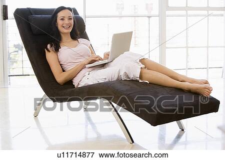 Woman sitting in chair using laptop smiling View Large Photo Image Stock Photo - Woman sitting in chair using laptop smiling. Fotosearch