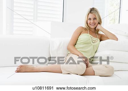 Stock Image - Woman sitting in living room. Fotosearch