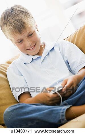 Young boy in living room with MP3 player smiling View Large Photo Image Stock Image - Young boy in living room with MP3 player smiling. Fotosearch