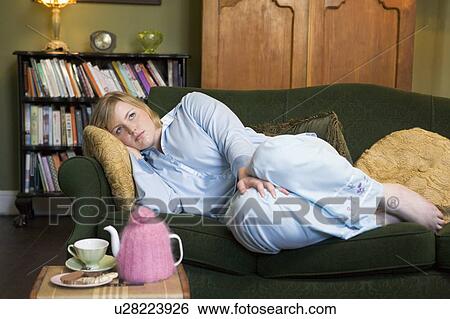 Young woman lying on sofa at home View Large Photo Image Stock Photograph - Young woman lying on sofa at home. Fotosearch