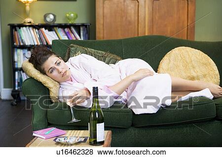 Stock Photo - Young woman lying on sofa smoking and drinking wine. Fotosearch