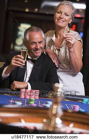 Stock Photo - Couple in casino playing roulette and smiling (selective focus). Fotosearch