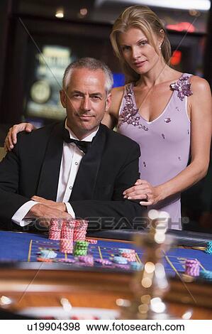 Stock Photo - Couple in casino playing roulette and smiling (selective focus). Fotosearch