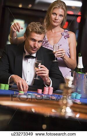 Stock Photo - Couple in casino playing roulette and smiling (selective focus). Fotosearch