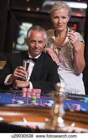 Stock Photo - Couple in casino playing roulette and smiling (selective focus). Fotosearch