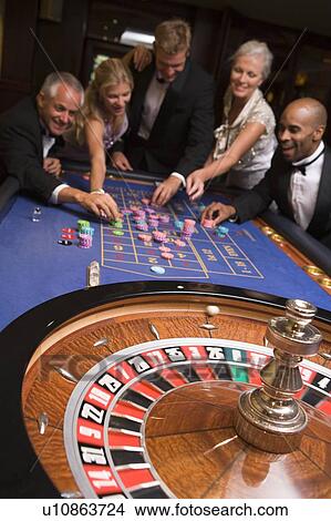 Group of people in casino playing roulette and smiling (selective focus) View Large Photo Image Picture - Group of people in casino playing roulette and smiling (selective focus). Fotosearch