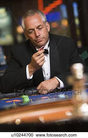 Man in casino playing roulette and looking at chip (selective focus) View Large Photo Image Stock Image - Man in casino playing roulette and looking at chip (selective focus). Fotosearch