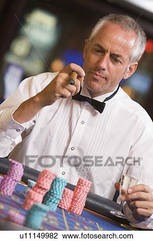Man in casino playing roulette and smoking cigar (selective focus) View Large Photo Image Stock Image - Man in casino playing roulette and smoking cigar (selective focus). Fotosearch
