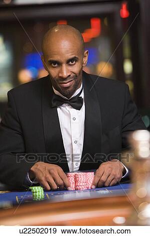 Stock Photo - Man in casino playing roulette smiling (selective focus). Fotosearch