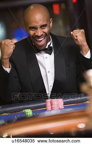 Stock Photography - Man in casino winning roulette and smiling (selective focus). Fotosearch