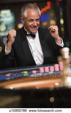 Stock Photograph - Man in casino winning roulette smiling (selective focus). Fotosearch