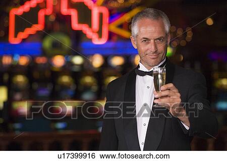 Stock Photograph - Man in casino with champagne smiling (selective focus). Fotosearch