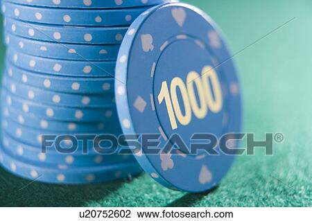 Stock Image - Poker chips piled on a poker table with one thousand chip showing (close up/selective focus). Fotosearch