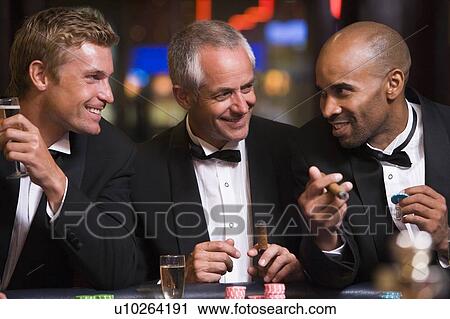 Three men in casino playing roulette and smiling (selective focus) View Large Photo Image Stock Image - Three men in casino playing roulette and smiling (selective focus). Fotosearch